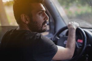 young man with headache behind wheel