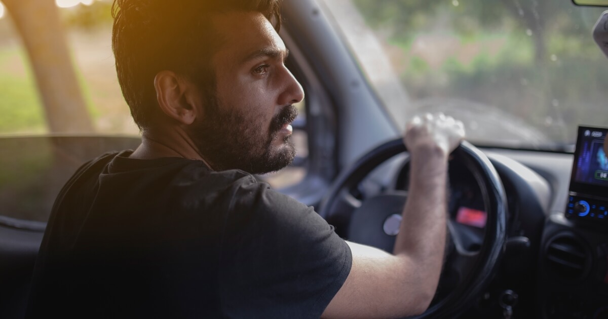 young man with headache behind wheel
