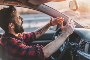 young man yelling and waving his hands while driving