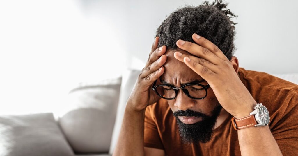 Young african American man holding his head and looking upset