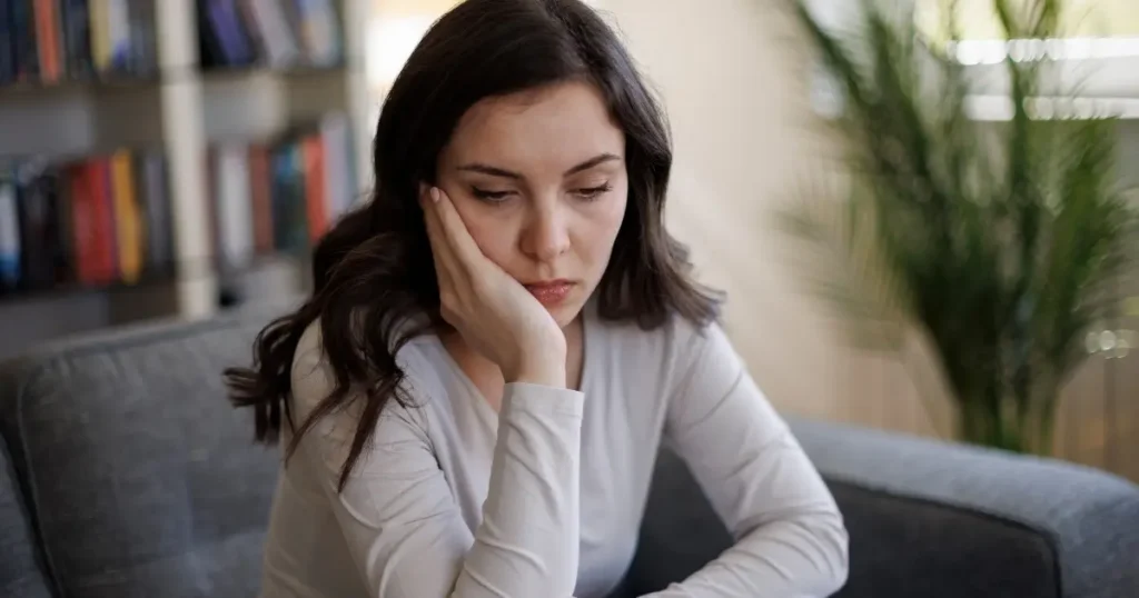 young woman resting her head in one hand and looking fatigued, depressed