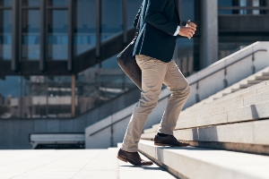 A man walking up the stairs into a corporate building.