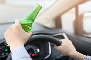 man-hands-with-green-beer-on-steering-wheel