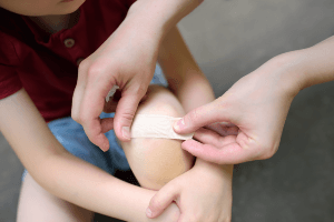mother placing a bandage on a child's knee