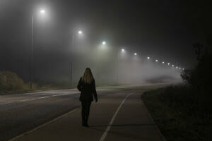 pedestrian walking on roadside at night
